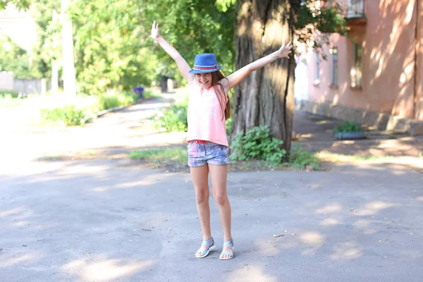 Abbastanza carino ragazza femminile bambino che salta e si diverte in cortile sulla strada . — Foto Stock