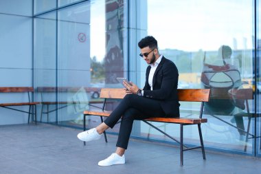 Arap takım elbiseli adam iş merkezinin yakınında güneş gözlüğü takıyor.