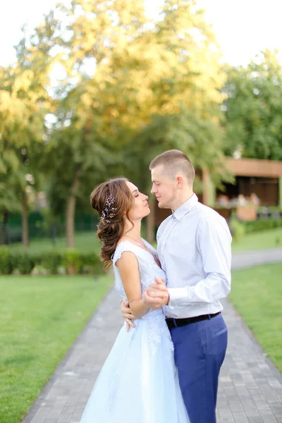 Joven novia caminando y besándose con novio caucásico en el jardín . — Foto de Stock