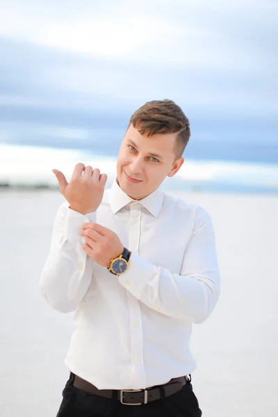 Young caucasian man wearing white shirt standing in winter steppe. — Stock Photo, Image