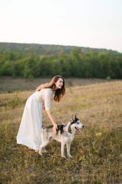 Beyaz bir gelin bozkırda köpekle yürür ve beyaz bir elbise giyer..