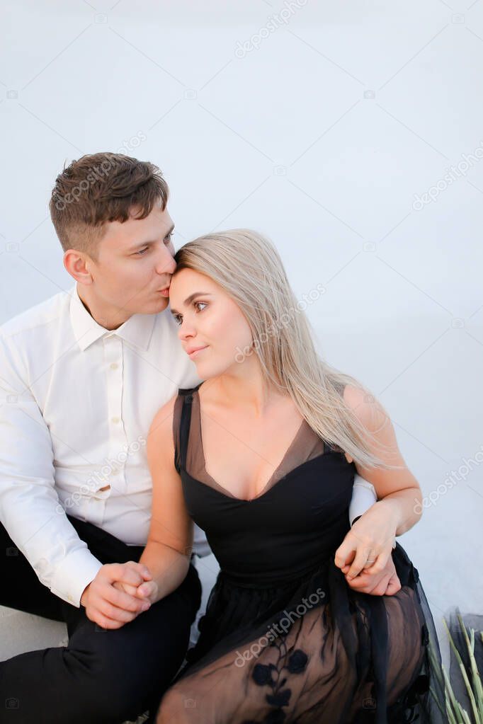 Young man hugging and kissing woman in black dress.