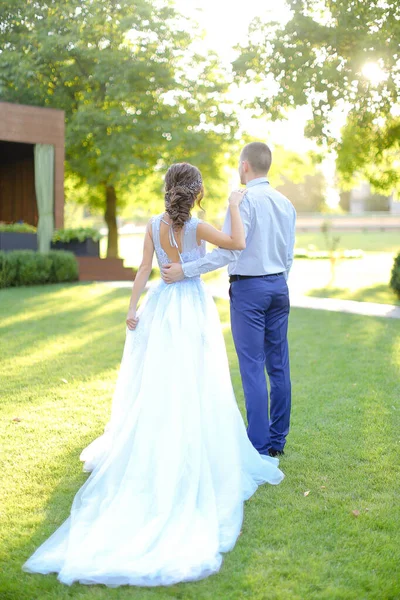 Visão traseira da noiva caucasiana e noivo andando no jardim . — Fotografia de Stock