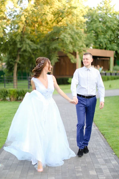 Fiatal szép menyasszony séta fehér vőlegény a kertben. — Stock Fotó