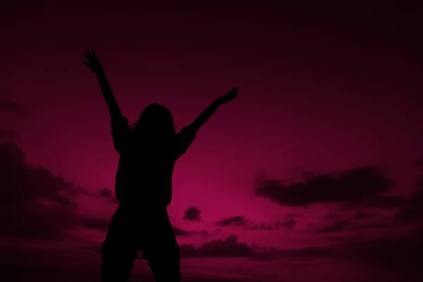 Female black silhouette with raised hands on violet sunset sky background in Bali. — Stock Photo, Image
