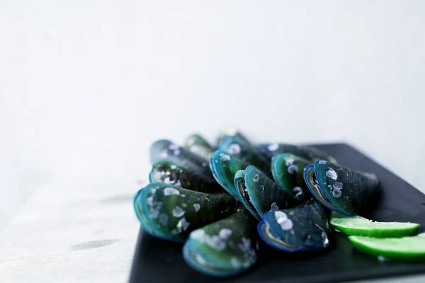 Exotic mussels on black square plate in white background. — Stock Photo, Image