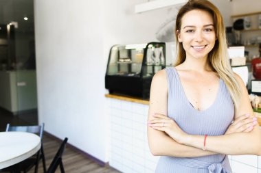 Kafe yöneticisi ayakta ve gülümsüyor..