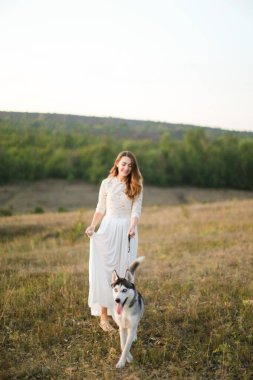Kafkasyalı genç gelin bozkırda köpekle yürüyor ve beyaz elbise giyiyor..