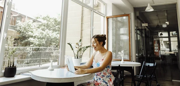 Joven mujer sorprendida navegando por Internet por ordenador portátil en la cafetería . — Foto de Stock