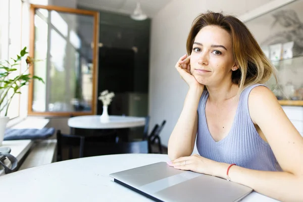 Young girl sitting at cafe with closed laptop. — Stock Photo, Image