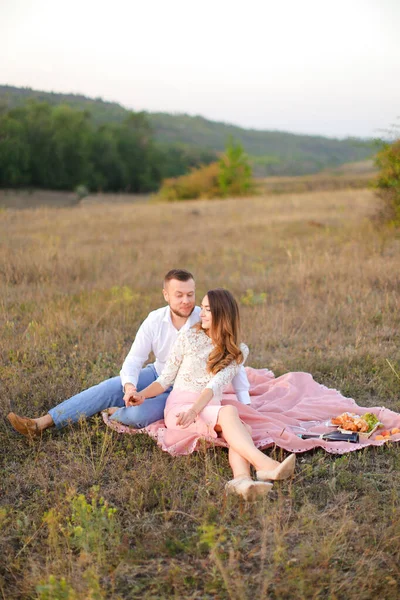 Giovane bella donna e uomo seduto su plaid rosa sulla natura . — Foto Stock