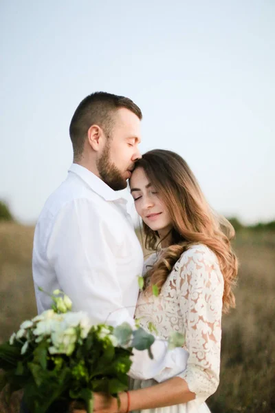 Sposa che abbraccia da vicino con mazzo di fiori sullo sfondo del campo . — Foto Stock