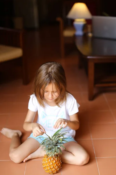 Niña jugando con piña y sentada en el suelo . — Foto de Stock