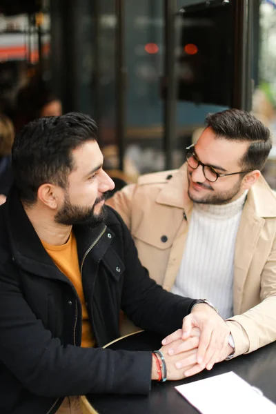 Двоє кактусових молодих геїв розмовляють в кафе і тримають руки . — стокове фото