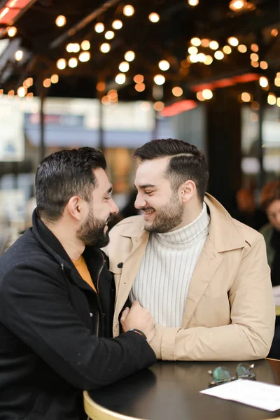 Кавказькі геї сидять у кафе, розмовляють і обіймають. — стокове фото