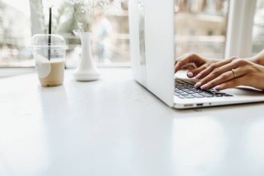 Ofisteki beyaz masada dizüstü bilgisayarda yazan eller..