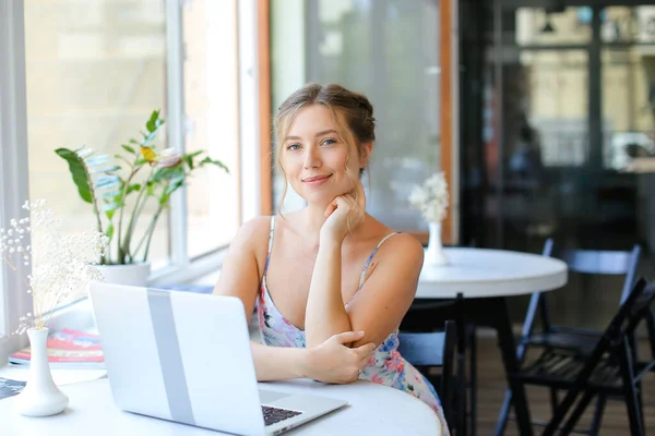 Estudiante sentada en la cafetería y navegando por internet por computadora portátil . — Foto de Stock