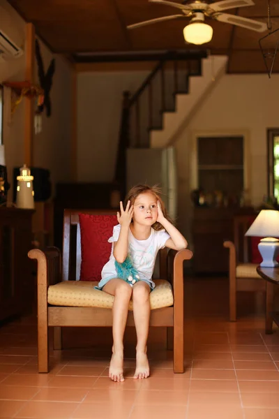 Niña sentada en silla con juguete en el salón . — Foto de Stock