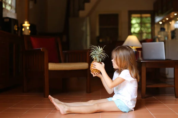 Niña americana sentada en el suelo y jugando con piña . — Foto de Stock