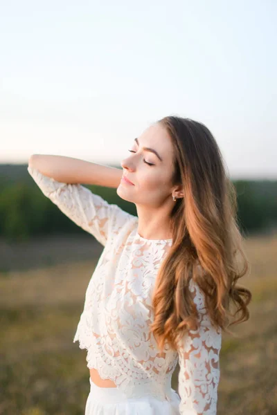 Portrait of caucasian blonde bride standing in steppe and wearing white dress. — Stockfoto