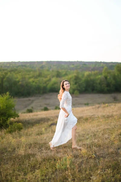 Caucasian young bride walking in steppe and wearing white dress. — Stock Photo, Image