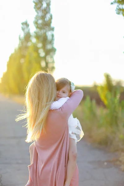 Blonde mother holding little female kid on road. — Stock Photo, Image