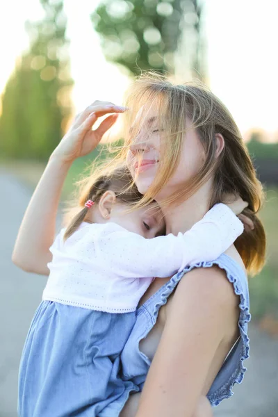 Blond moeder houden vrouwelijke kind en lopen op de weg. — Stockfoto