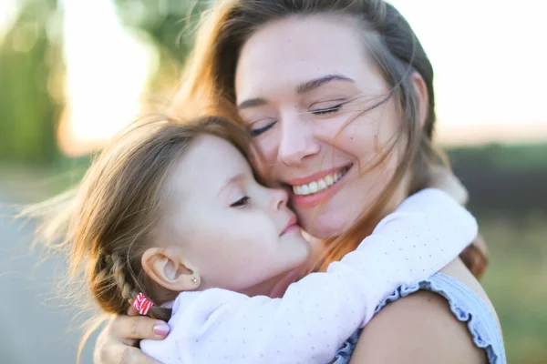 Portraitr of woman holding female kid and walking on road. — Stockfoto