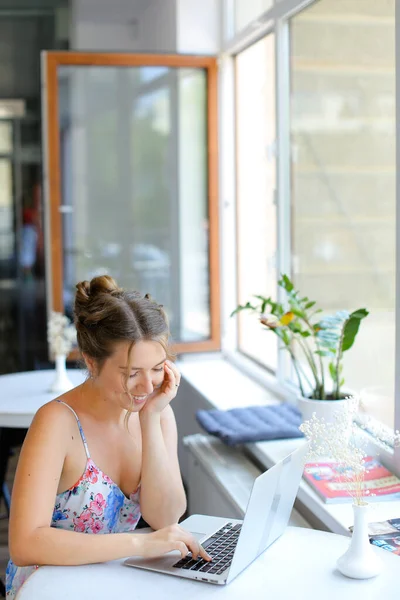 Estudiante europea sentada en la cafetería y navegando por internet por computadora portátil . — Foto de Stock