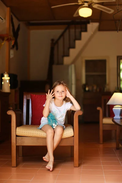 Niño pequeño sentado en silla con juguete en la sala de estar . — Foto de Stock