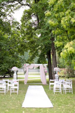 Düğün pahalı kemeri, parkta güller ve sandalyelerle süslenmiş..