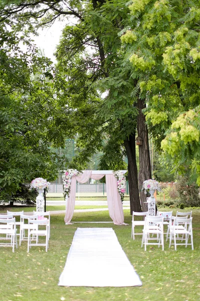 Boda arco caro, decorado con rosas y sillas en el parque . — Foto de Stock