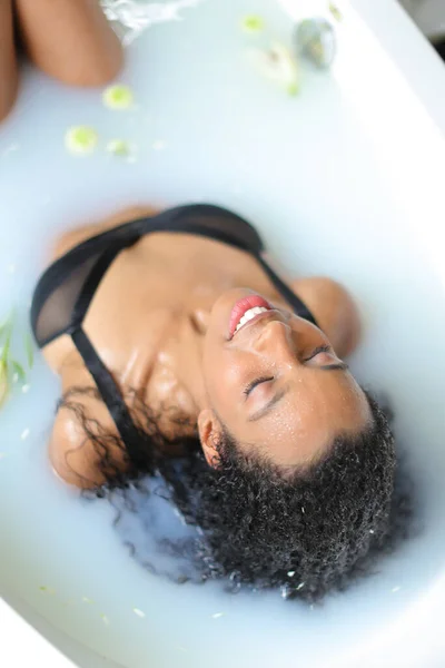 Jong zwart meisje het nemen van melk bad en het dragen van badpak. — Stockfoto