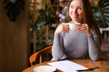 Çay içen genç kız, vize başvurusu ve pasaport masada..