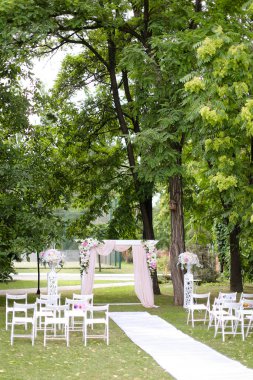 Düğün kemeri, parkta güllerle ve sandalyelerle süslenmiş..