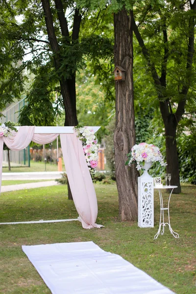 Łuk ślubny, ozdobiony różami i krzesłami w parku. — Zdjęcie stockowe