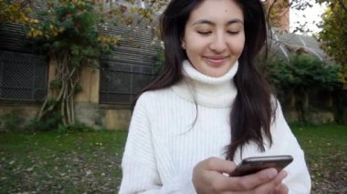 Şehirde telefon kullanan genç Asyalı kadını kapat. Güzel Çinli kız cep telefonuyla yazıyor. Chengdu Çin 'de bir akşam.