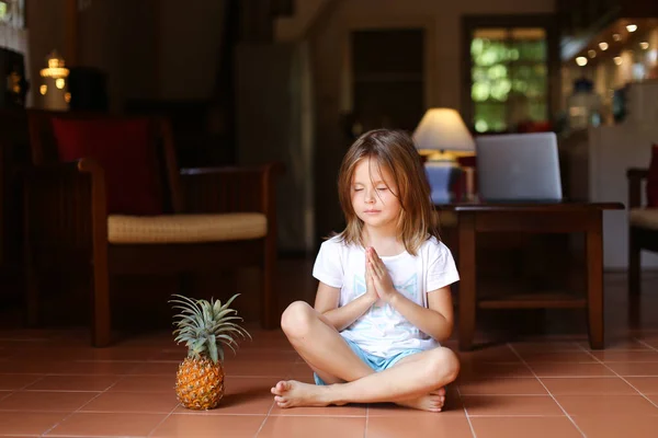 Niña sentada en el suelo con piña y meditando . — Foto de Stock