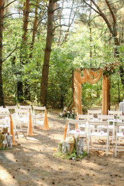 Sarı harika düğün sunağı ve bahçede beyaz sandalyeler.