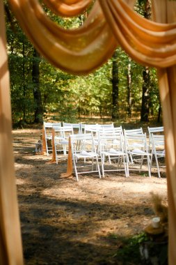 Ormanda sunağın yanında beyaz düğün sandalyeleri.