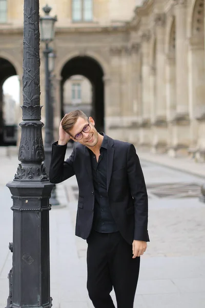 Junger gut aussehender Mann spaziert durch Paris und trägt schwarzen Anzug. — Stockfoto