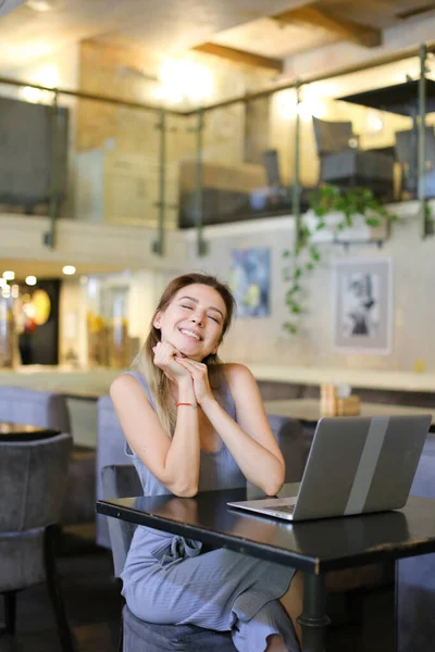 Молодая девушка сидит в кафе и серфинг интернет на ноутбуке . — стоковое фото