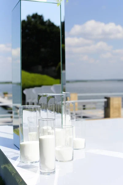 結婚式の祭壇の上の白いろうそくと鏡、背景の湖. — ストック写真