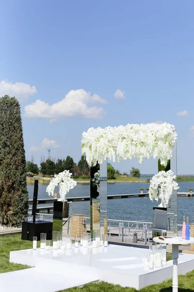 背景に湖と白い結婚式のアーチ. — ストック写真