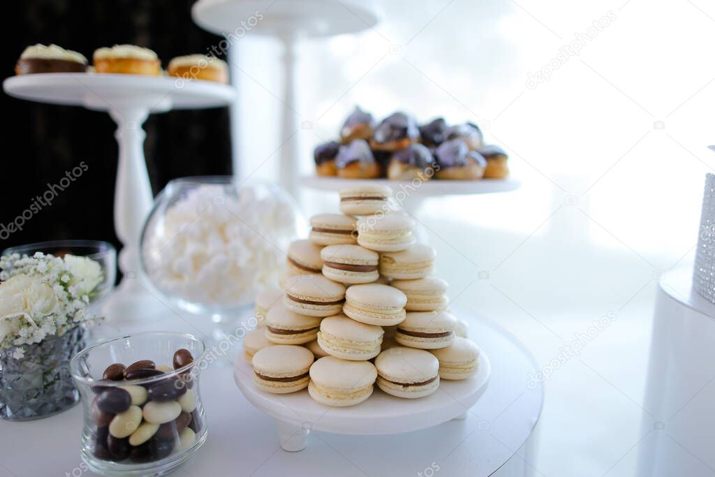 Yummy white macaroons and desserts on candy bar.
