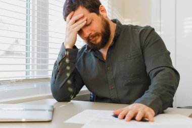 Ofiste dokümanlarla çalışmaktan yorgun düşünce inceliği, masadaki kapalı dizüstü bilgisayar.