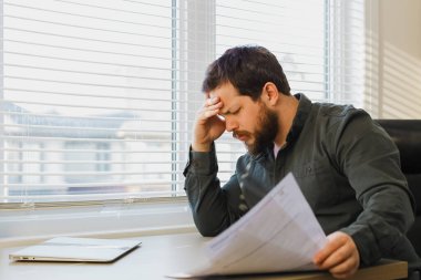 Bitkin işadamı dometleri dokümantasyonda dolduruyor, bilgisayarı masada kapatıyor..