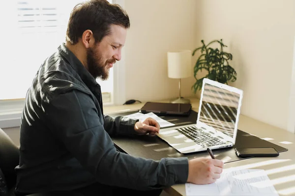 Empresário preenchendo documentos e trabalhando com laptop . — Fotografia de Stock