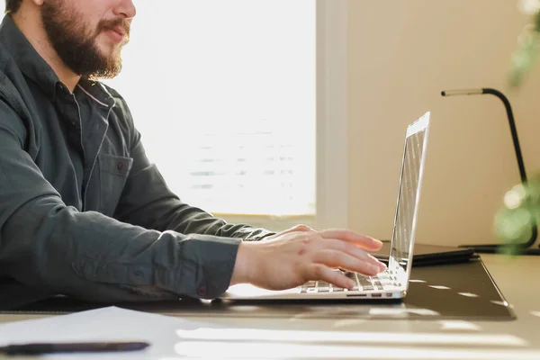 Gerenciador de conteúdo masculino escrevendo artigo no laptop no escritório . — Fotografia de Stock