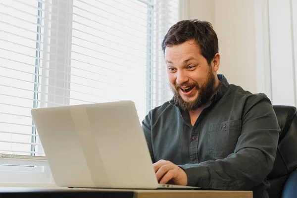 Financiador sorrindo bem sucedido sentado no escritório com laptop perto da janela . — Fotografia de Stock